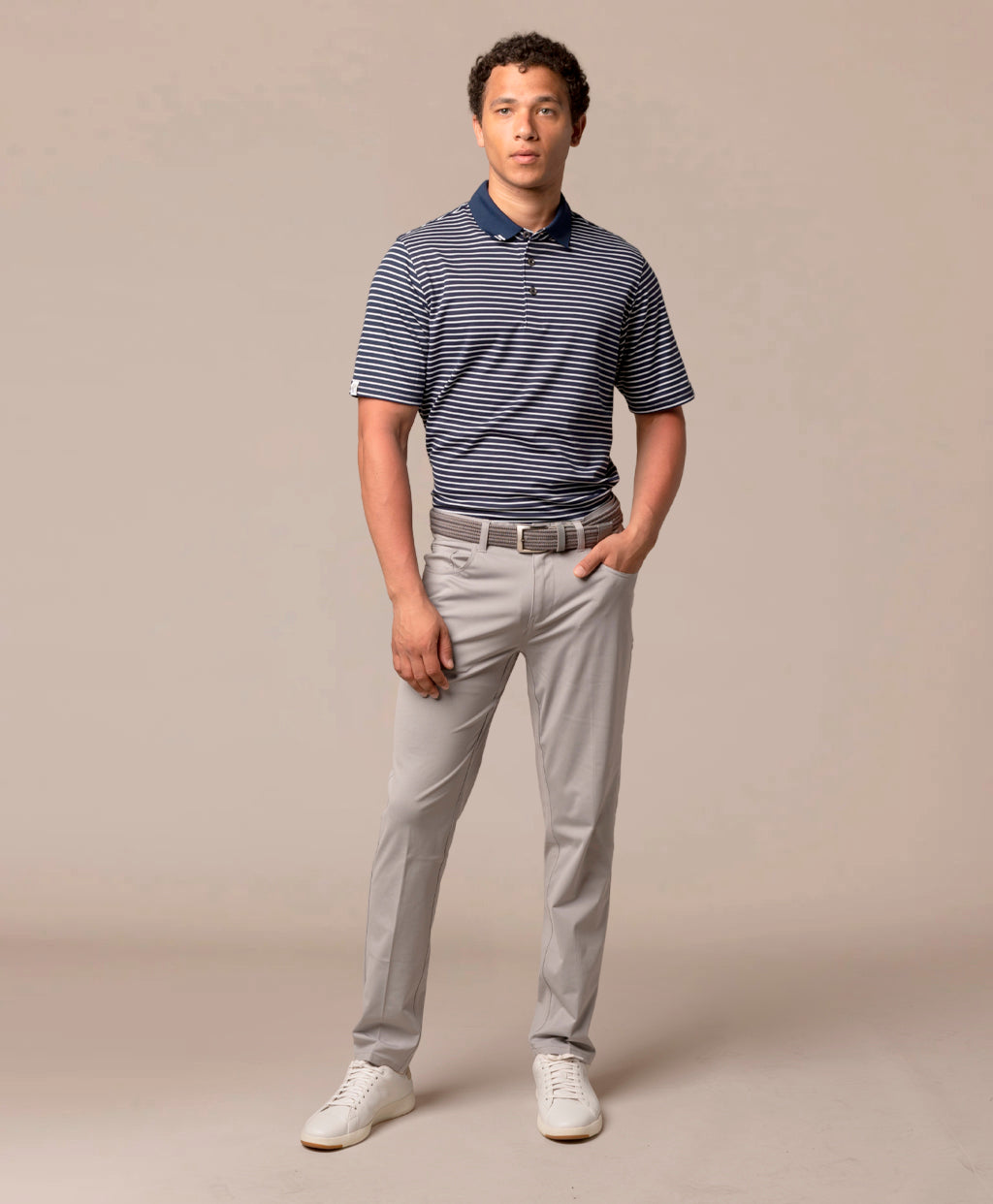 Man wearing a striped polo shirt and light gray pants