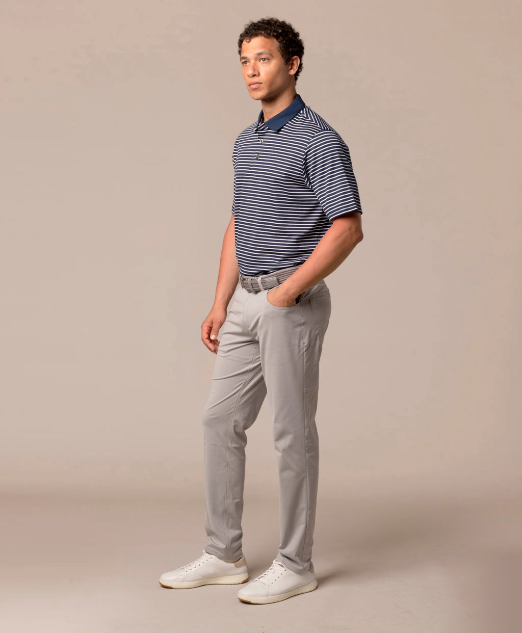 Man wearing a striped polo shirt and light gray pants