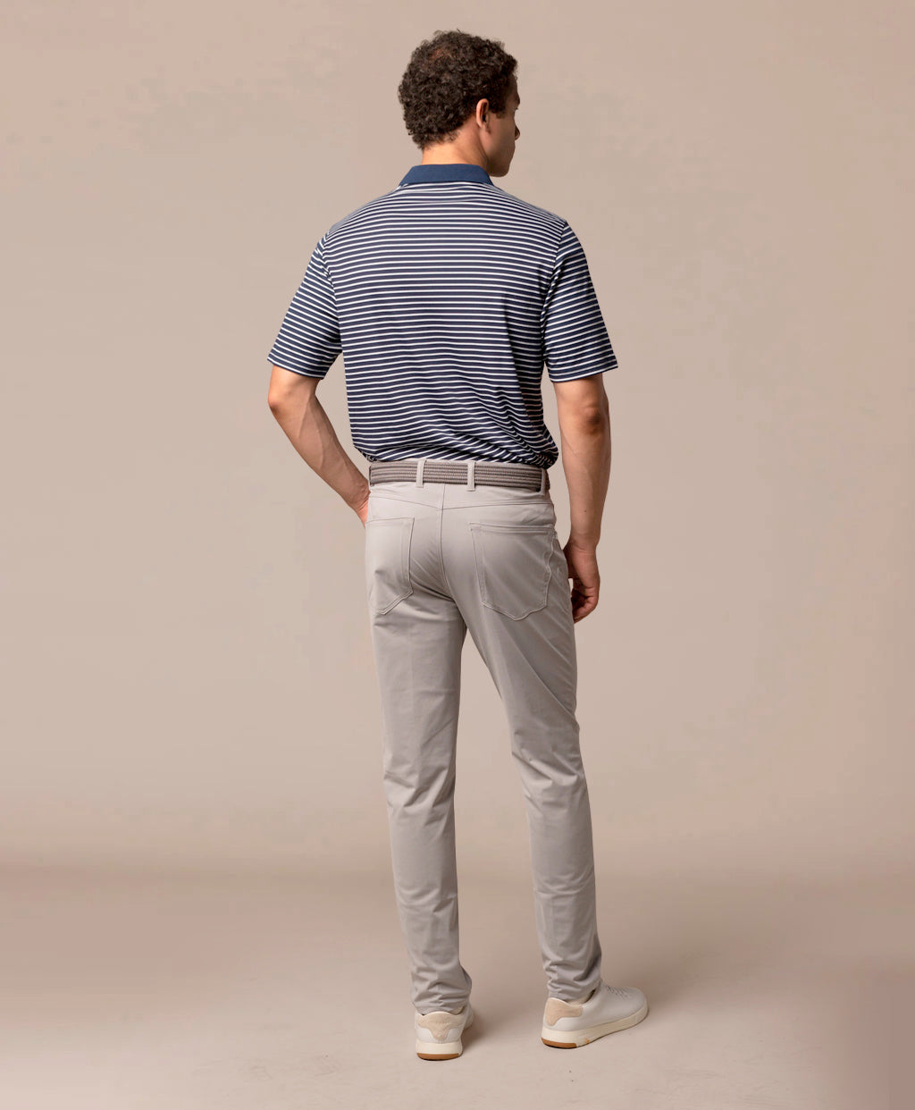 Man wearing a striped polo shirt and light gray pants