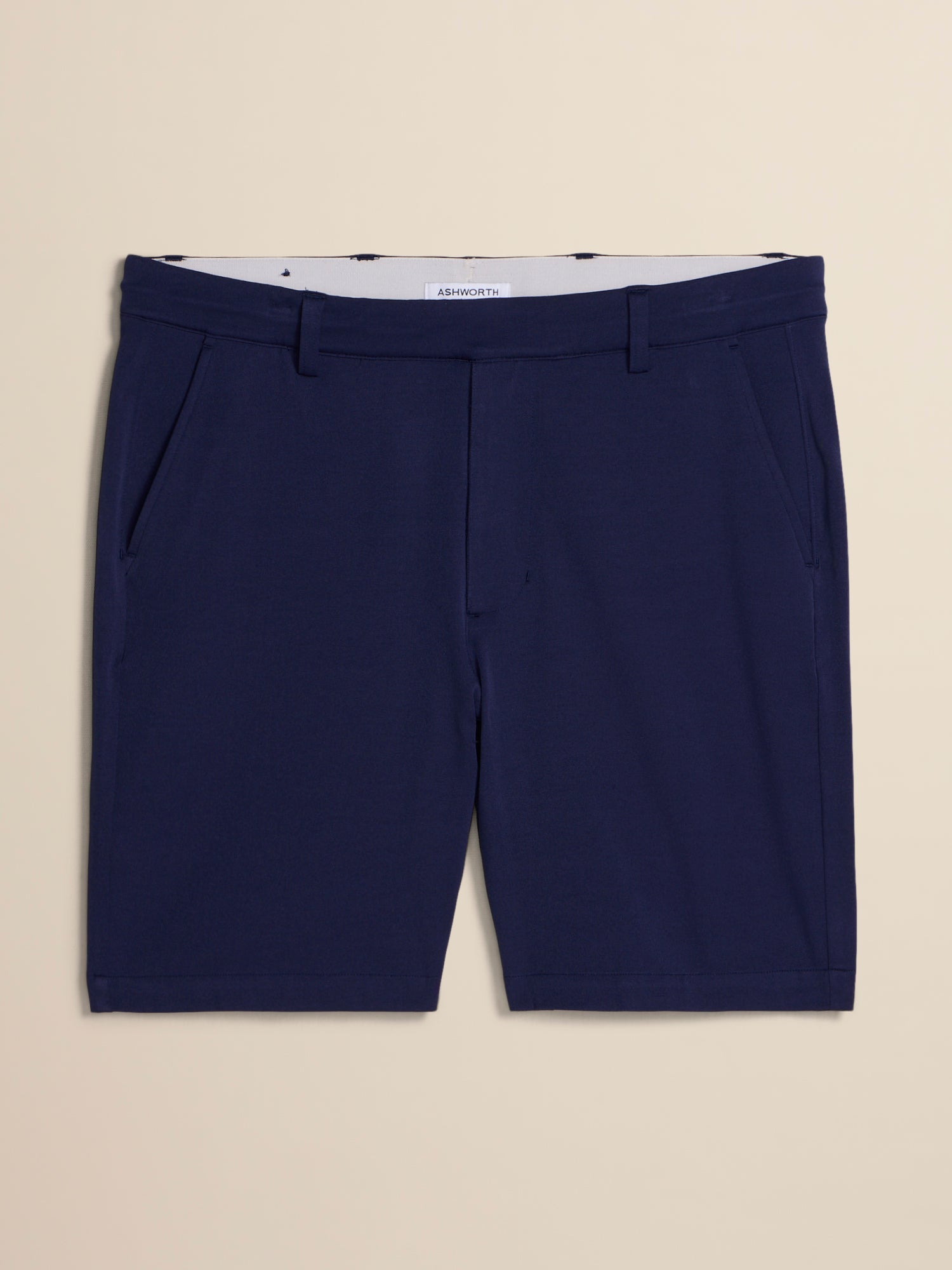 A pair of navy blue tailored shorts with a white inner waistband, laid flat against a light beige background.