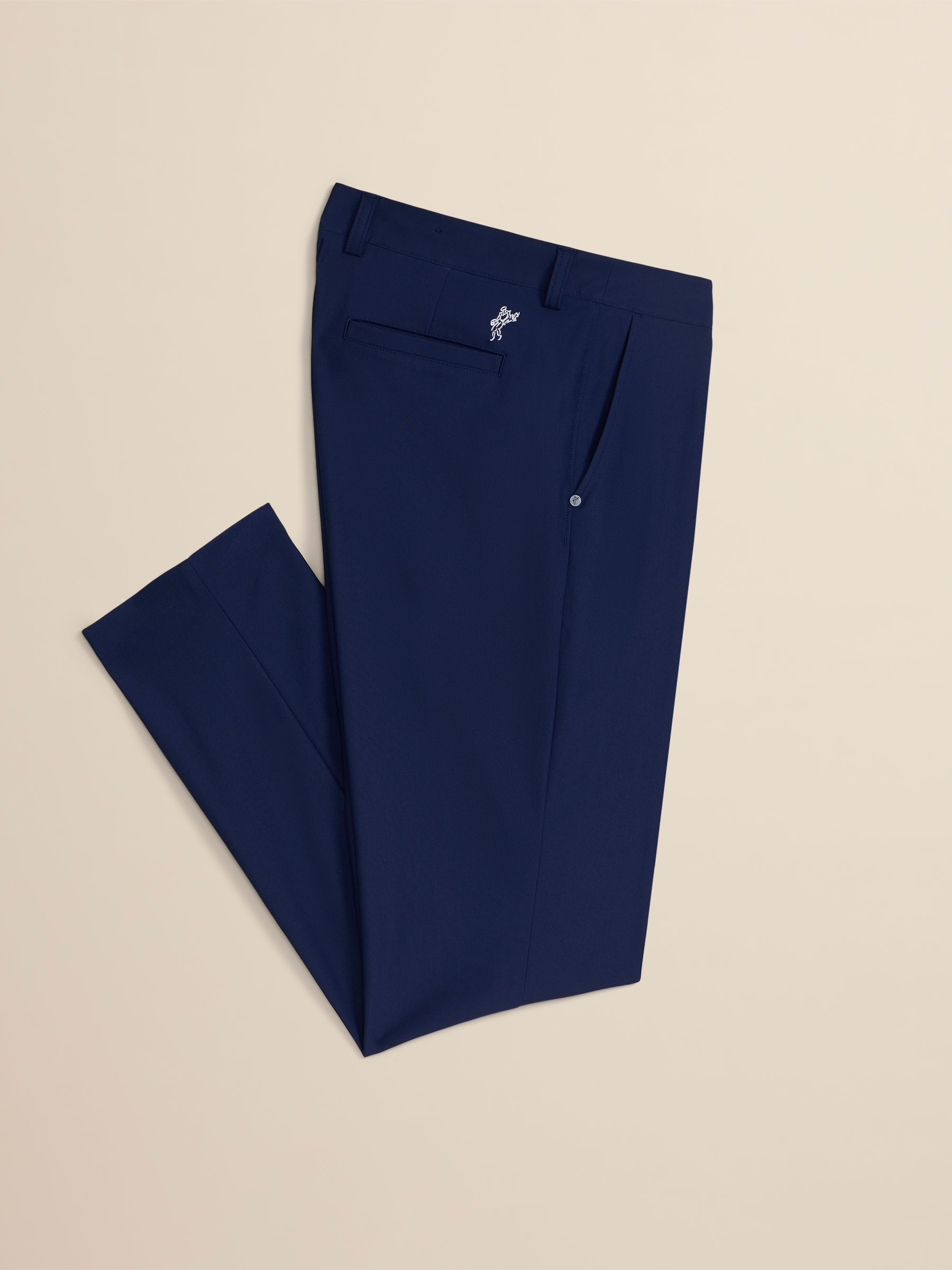 Navy blue pants with a brand logo on a beige background