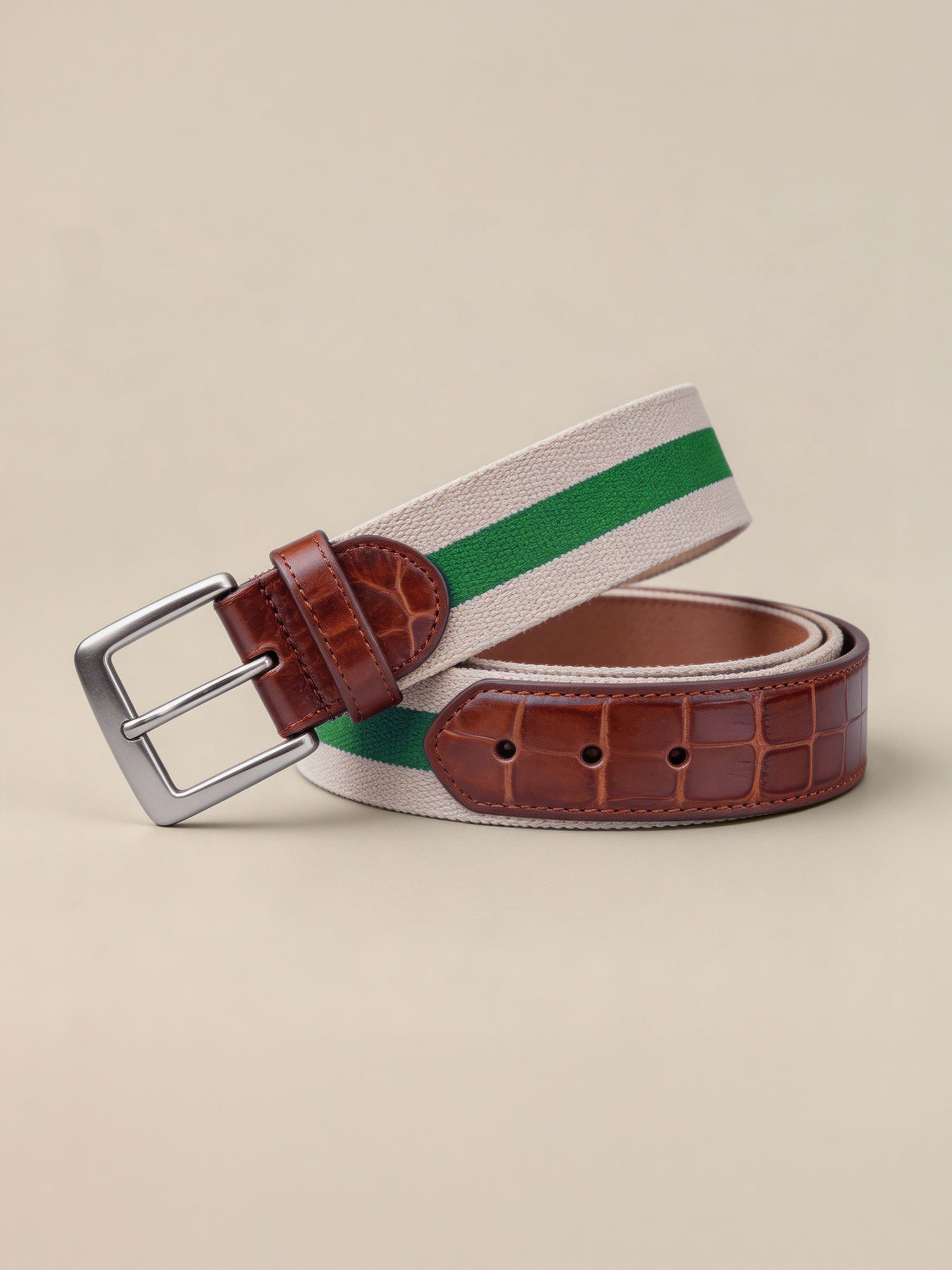 Woven belt with green stripe and brown leather buckle on beige background